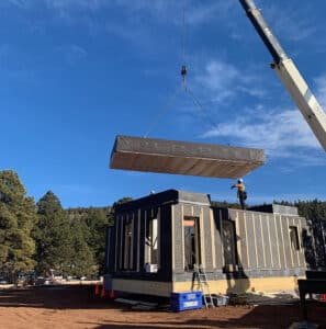 A very tall rrane arm lowers the roof onto a prefabricated metal building.