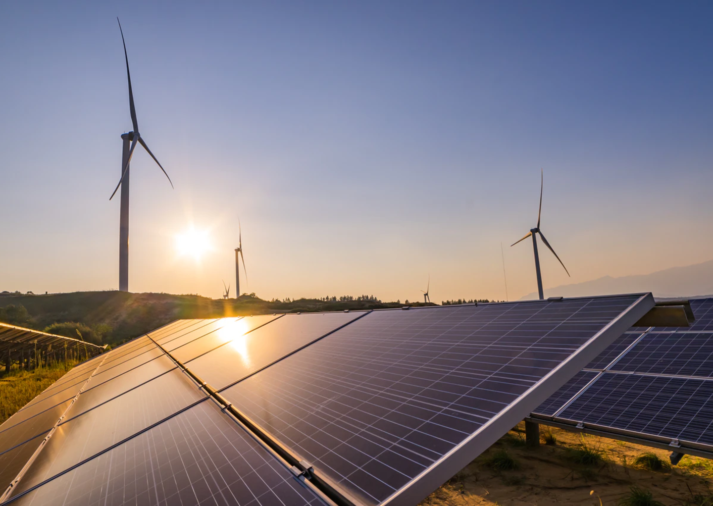 Solar panels and windmills at sunset