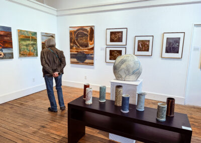 Indoor studio with pottery art on table and print art on walls.