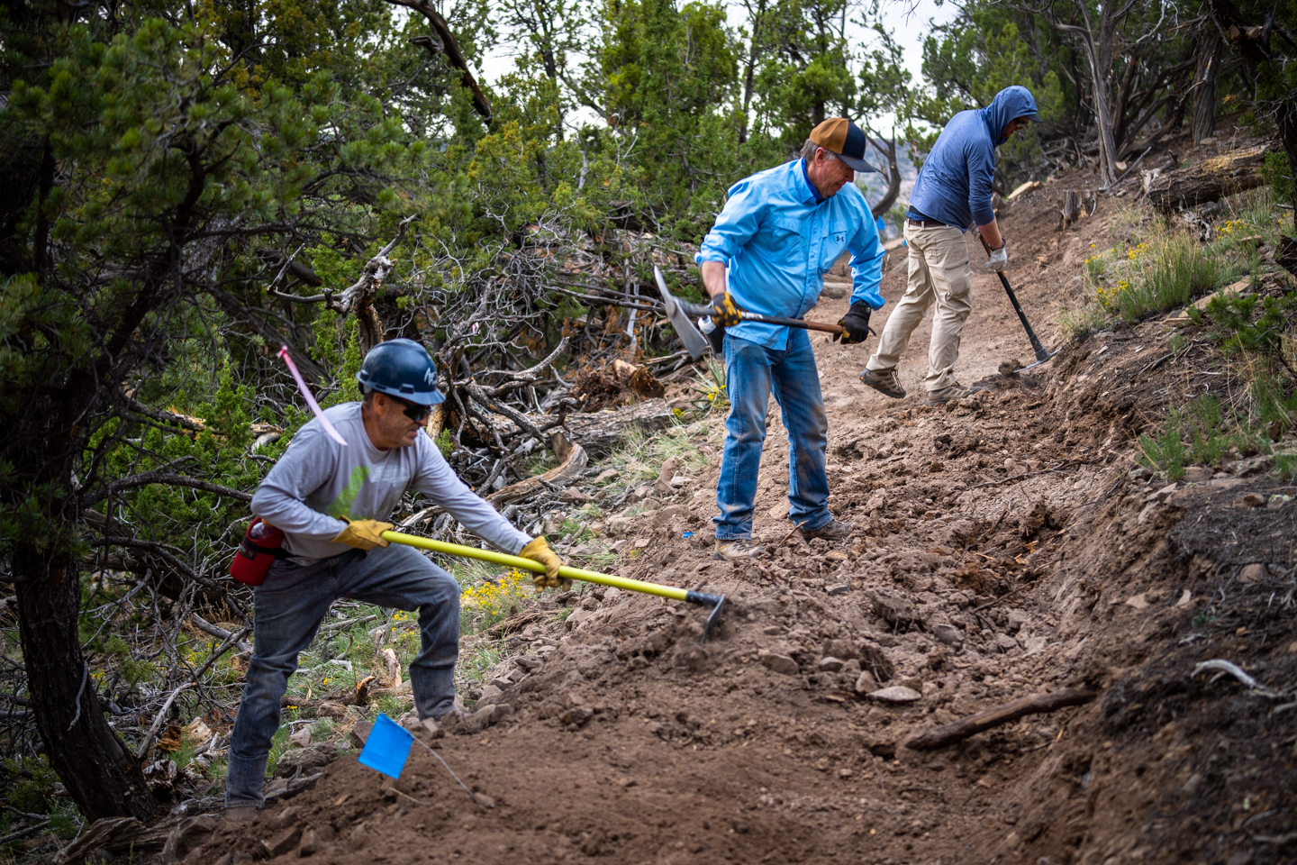 Three people are doing trail work