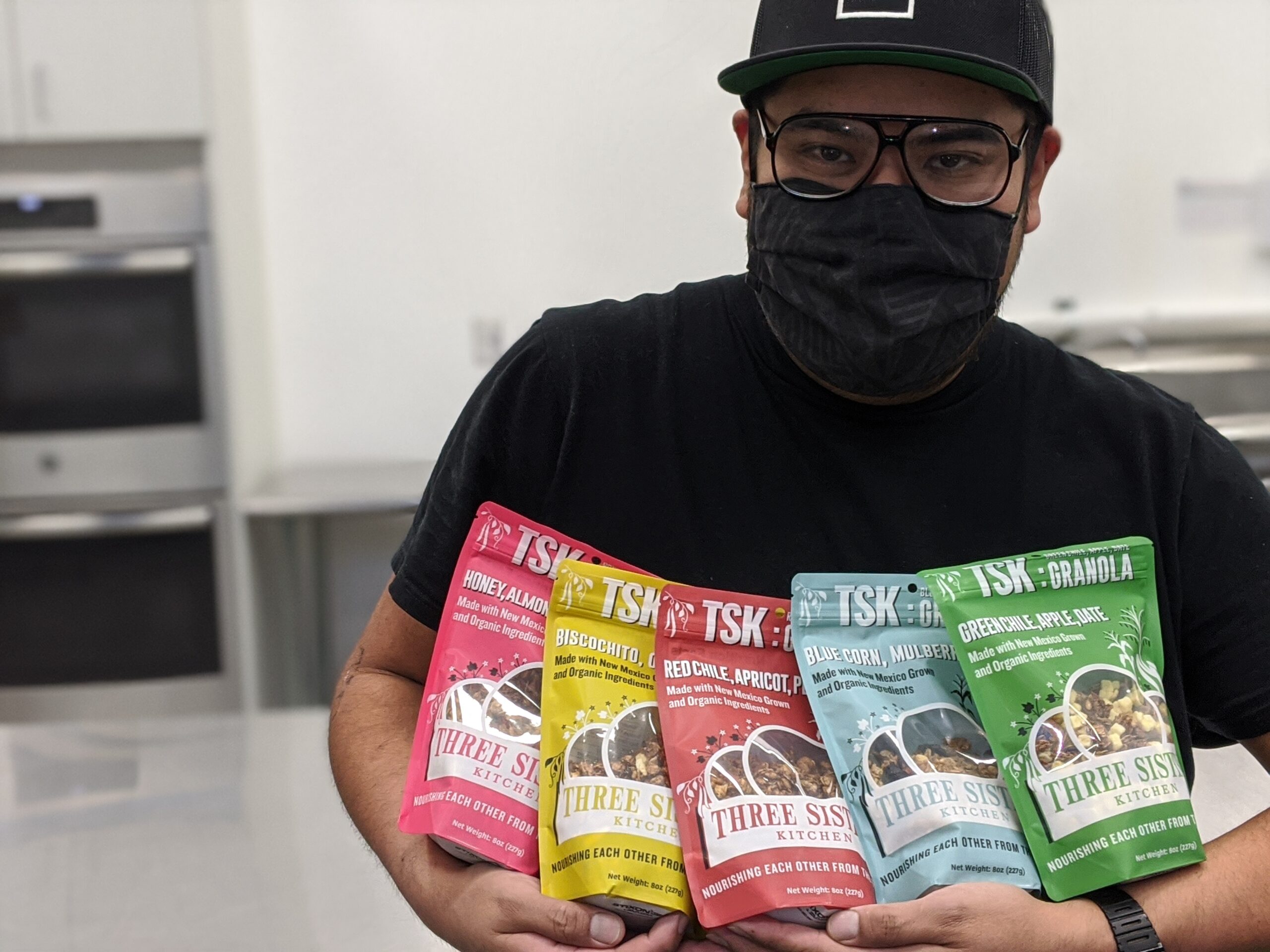 Kitchen worker holds the small colorful packages of finished granola ready for sale.