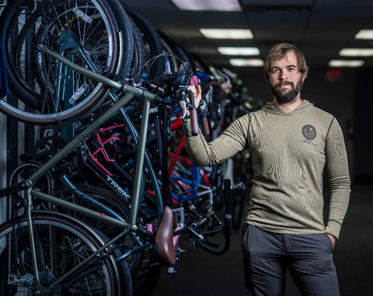 Man stands beside a rack of hanging bicycles